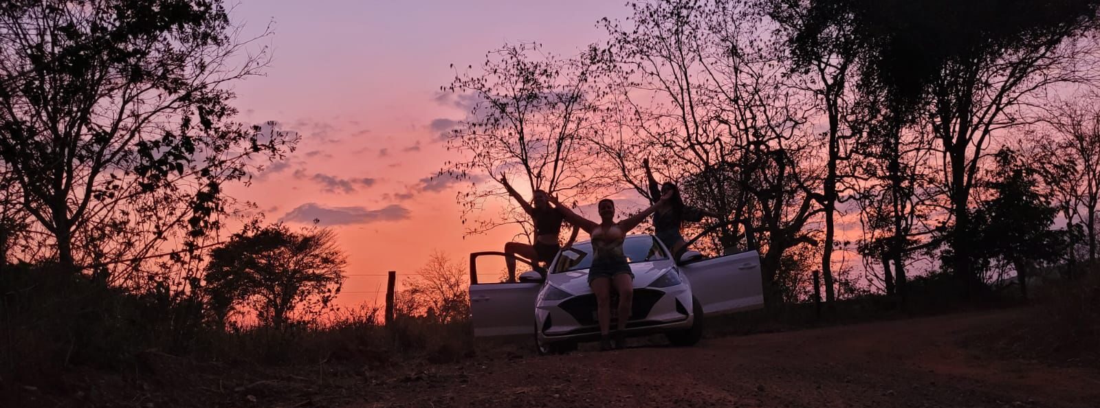 Pôr do sol do pantanal, carro GOL parado de frente com 3 três pessoas em pose no pantanal