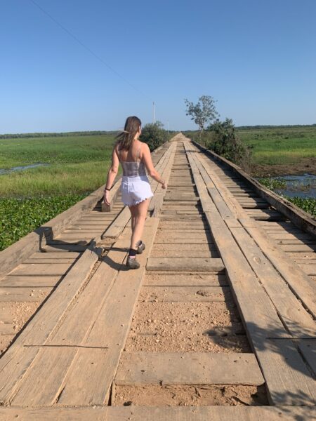 Ponte no Pantanal com moça caminhando de costas
